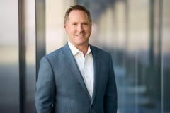 partner executive headshots with windows behind him