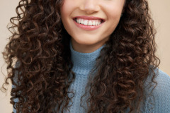cute curl hair model headshot on beige background in studio