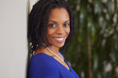 nautral light headshot in outdoor setting in washington dc wearing a bright blue dress shirt and pearl necklace