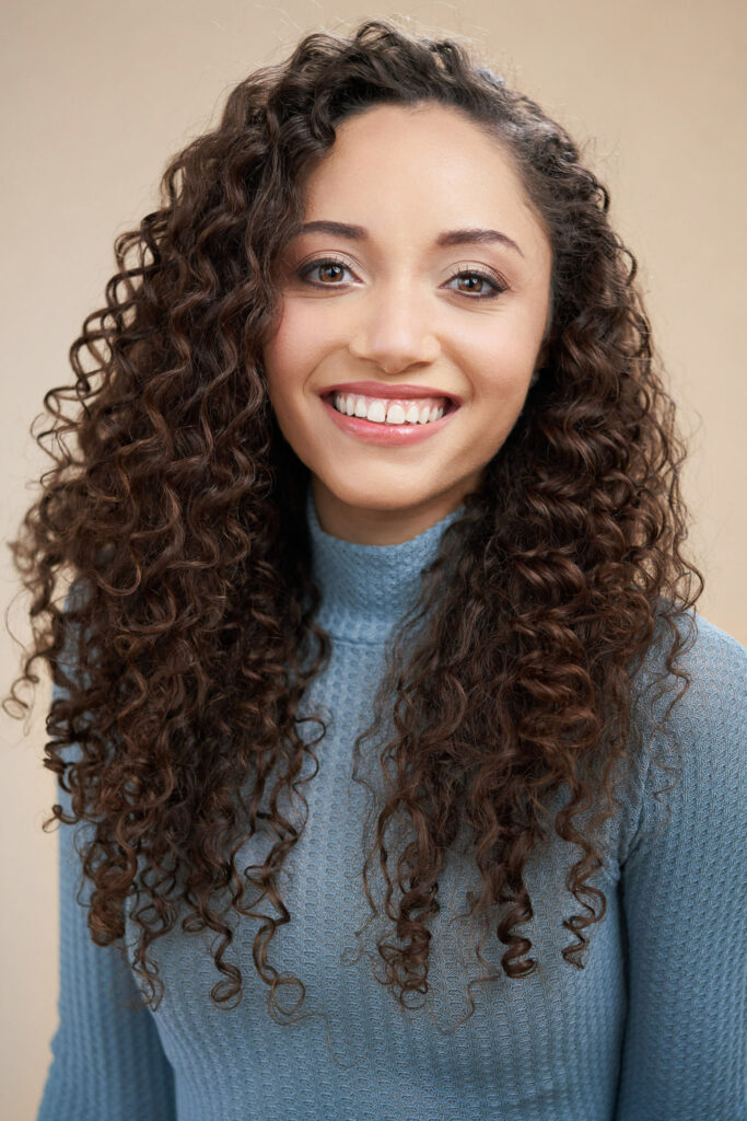 cute curl hair model headshot on beige background in studio